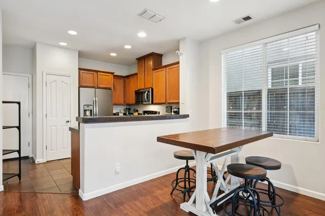 a kitchen with stainless steel appliances kitchen island granite countertop a refrigerator a stove a sink dishwasher with a dining table and chair with wooden floor