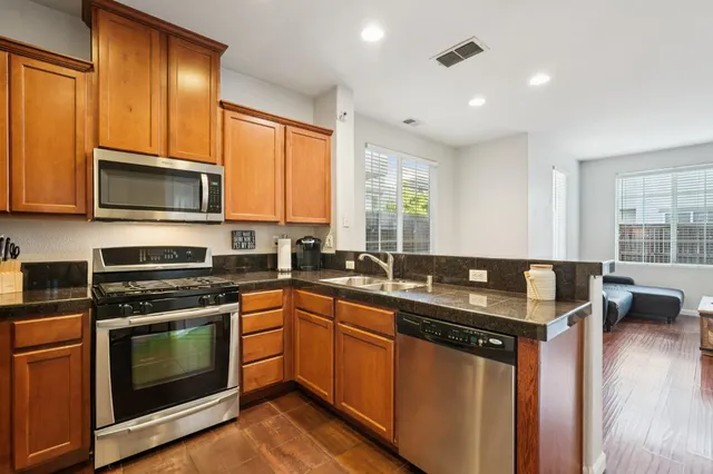 a kitchen with granite countertop a sink a stove top oven and cabinetry