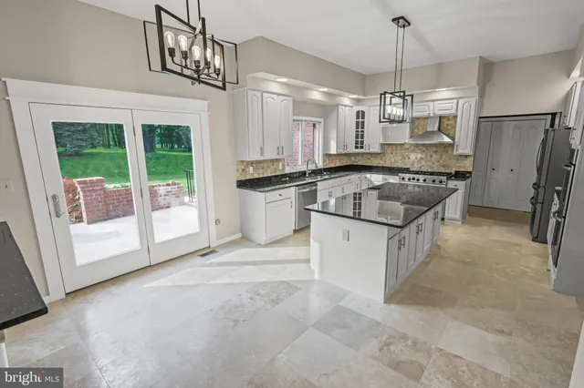 a kitchen with stainless steel appliances granite countertop a sink a stove a refrigerator cabinets and chairs