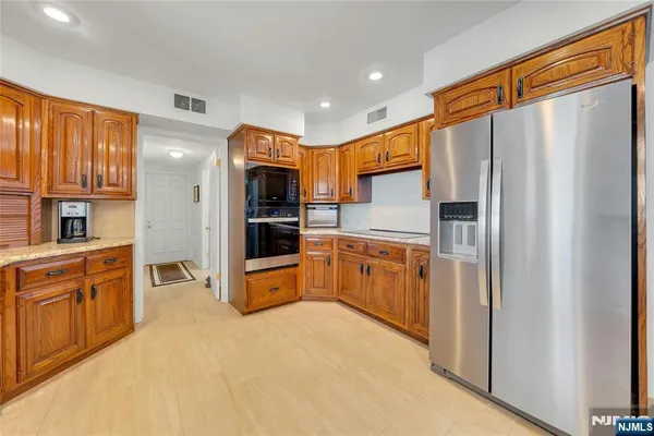 a large kitchen with stainless steel appliances granite countertop a refrigerator a sink dishwasher a oven and a dining table with wooden floor