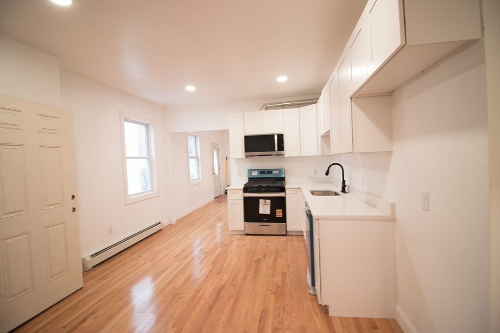 58 Willow Street Lowell, MA 01852 - Photo 4 of 21 a kitchen with a sink a counter top space stainless steel appliances and a window