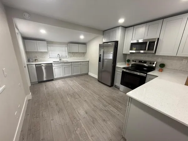 a kitchen with a refrigerator a stove top oven a sink and dishwasher with wooden floor