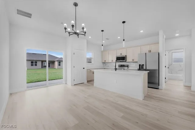 a view of a kitchen with granite countertop stainless steel appliances and a chandelier
