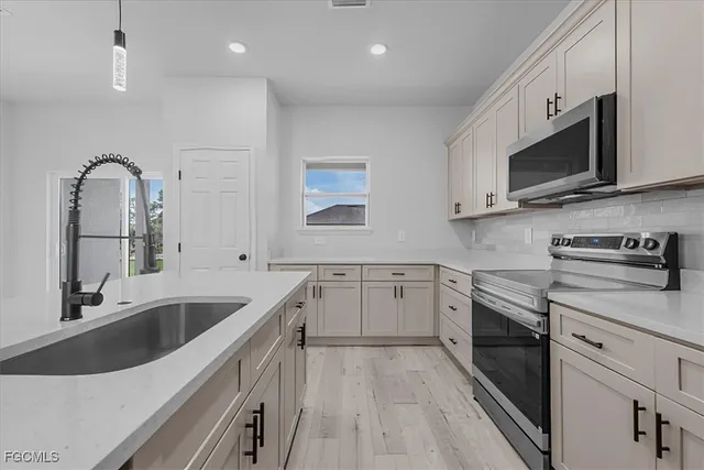 a kitchen with stainless steel appliances granite countertop a sink and a stove top oven with wooden floor