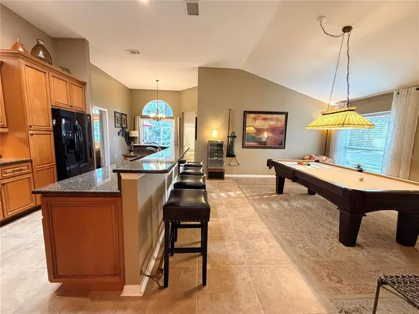 a living room with furniture a table and kitchen view