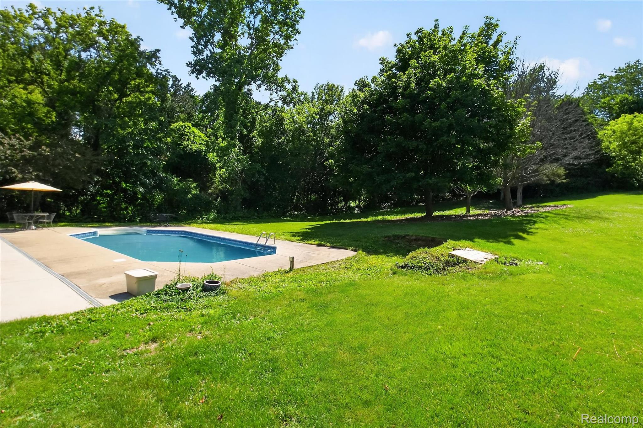 8114 Chilson Road Pinckney, MI 48169 - Photo 26 of 32 Expansive lawn area featuring an in-ground swimming pool with surrounding concrete decking
