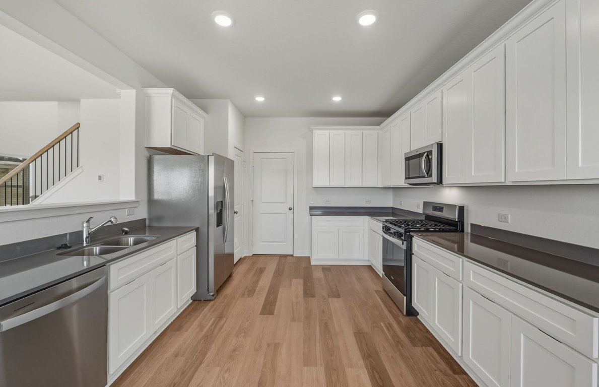 172 Golden Bell Way Buda, TX 78610 - Photo 7 of 24 a kitchen with stainless steel appliances granite countertop a sink stove and refrigerator