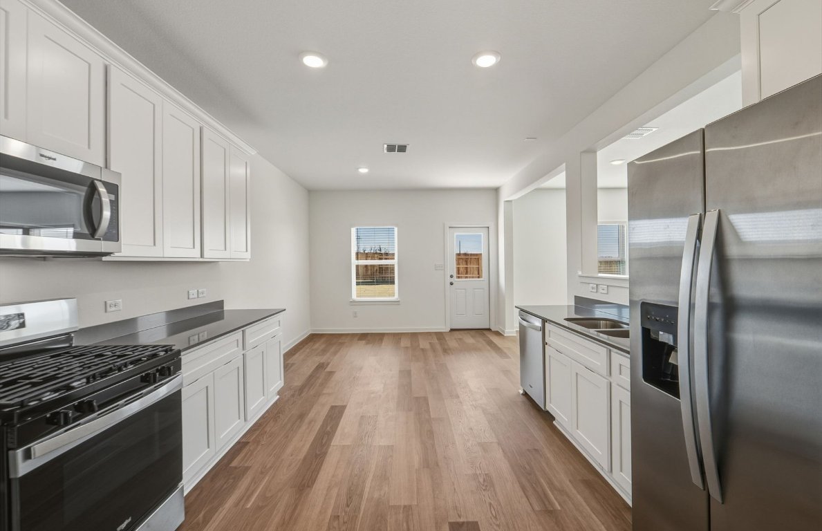 172 Golden Bell Way Buda, TX 78610 - Photo 8 of 24 a kitchen with stainless steel appliances granite countertop a stove and a refrigerator
