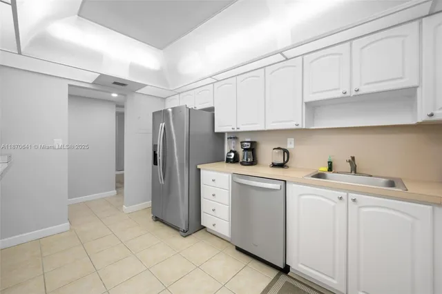 a kitchen with white cabinets and refrigerator
