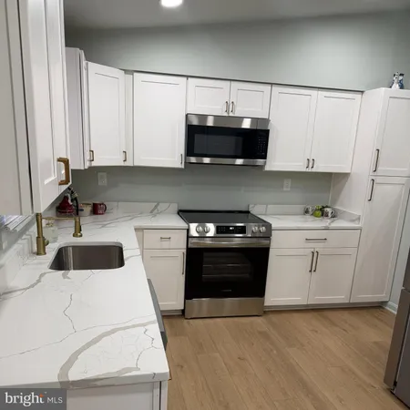 a kitchen with stainless steel appliances a sink stove and white cabinets