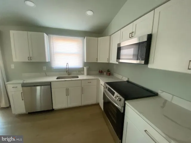 a kitchen with white cabinets sink and window