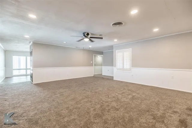 an empty room with windows and ceiling fan