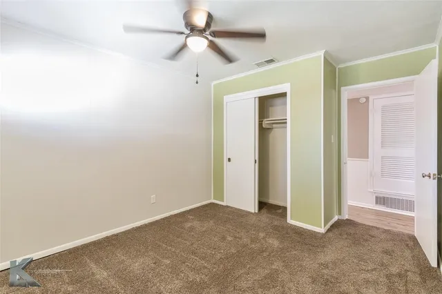 an empty room with closet and a ceiling fan