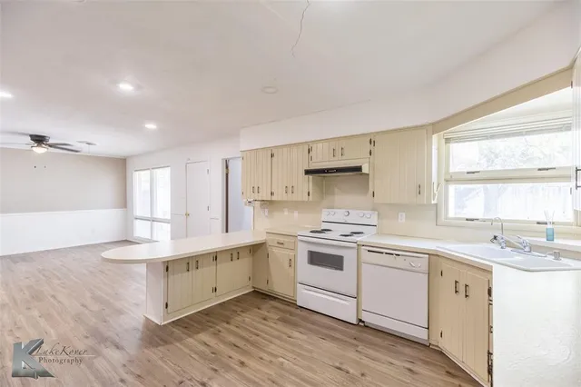 a kitchen with white cabinets appliances and a window