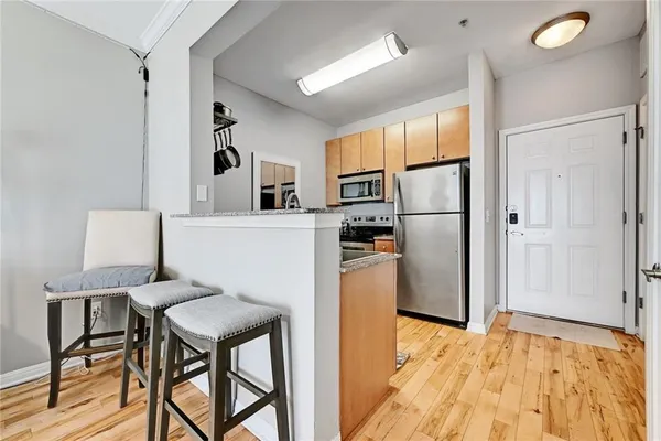 a kitchen with stainless steel appliances refrigerator stove dining table and chairs