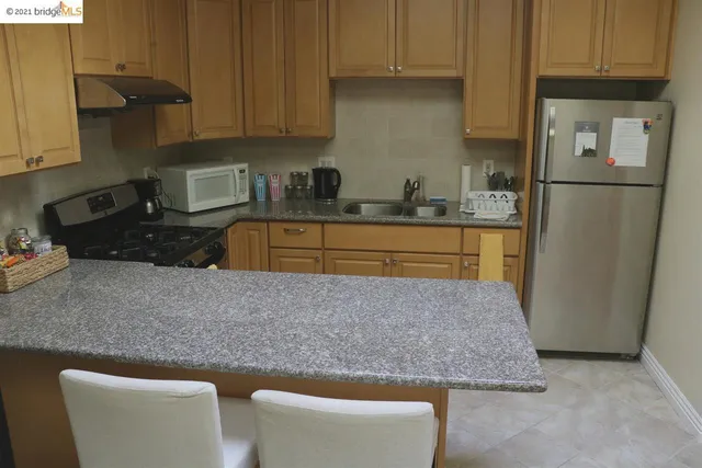 a kitchen with stainless steel appliances granite countertop a refrigerator a stove a sink and white cabinets with wooden floor