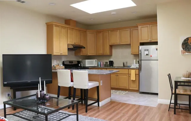 a kitchen with stainless steel appliances granite countertop a sink a stove a refrigerator cabinets and a window