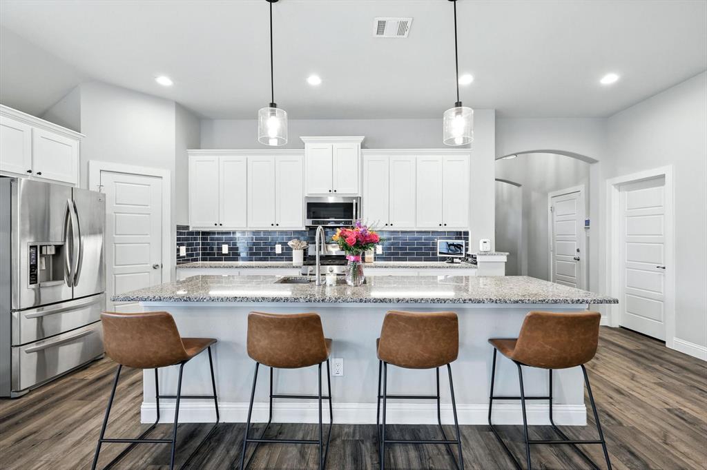 705 Chaparral Road Sanger, TX 76266 - Photo 11 of 38 a kitchen with stainless steel appliances kitchen island granite countertop a dining table chairs refrigerator and microwave