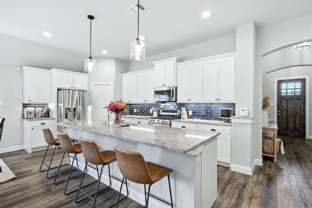 705 Chaparral Road Sanger, TX 76266 - Photo 12 of 38 a kitchen with stainless steel appliances granite countertop a stove top oven a refrigerator a sink and chairs