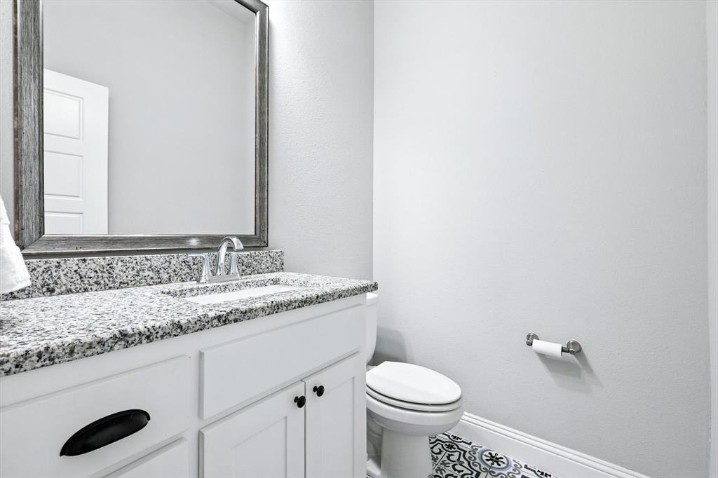 705 Chaparral Road Sanger, TX 76266 - Photo 18 of 38 a bathroom with a granite countertop sink and a toilet