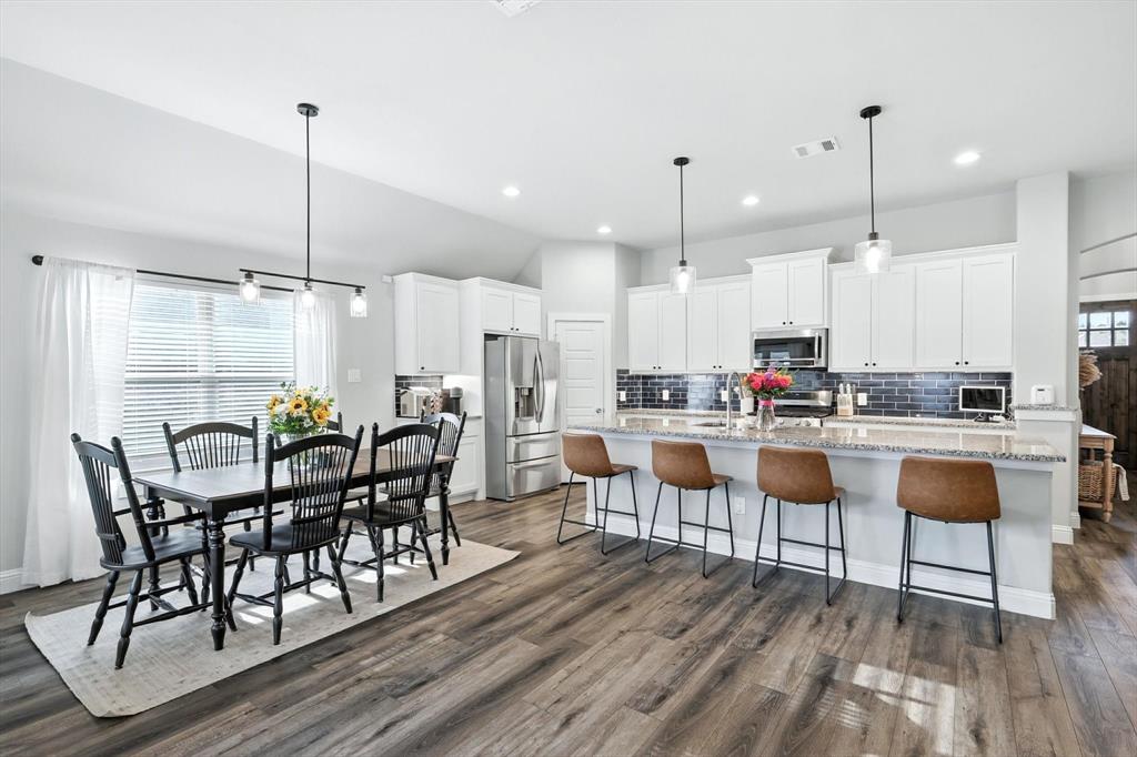 705 Chaparral Road Sanger, TX 76266 - Photo 10 of 38 a kitchen with stainless steel appliances kitchen island granite countertop a dining table chairs and white cabinets