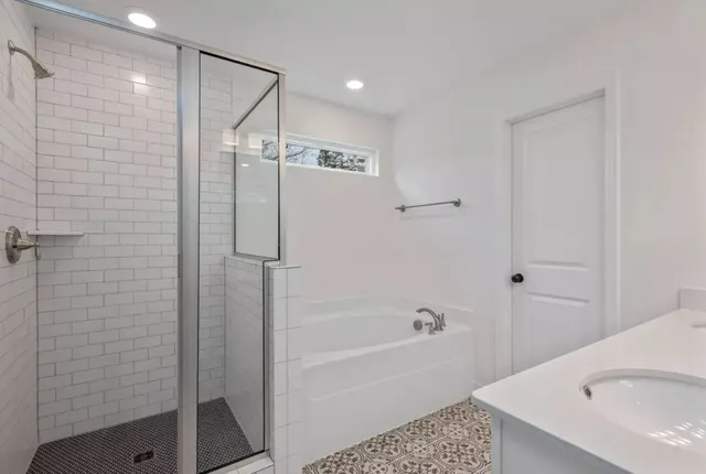 a bathroom with a tub a sink and a shower