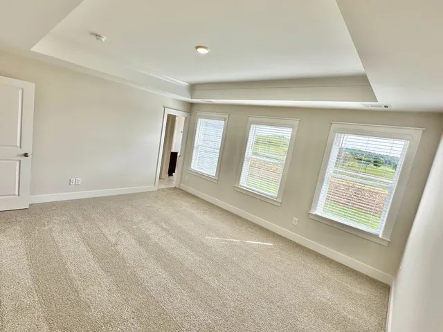 a view of an empty room with window and a kitchen