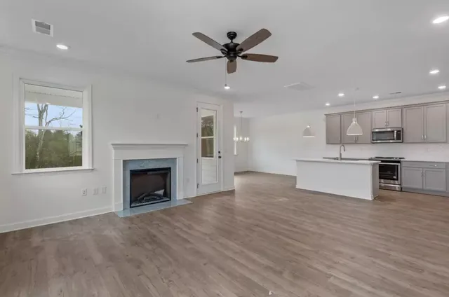 a view of an empty room with kitchen and a window