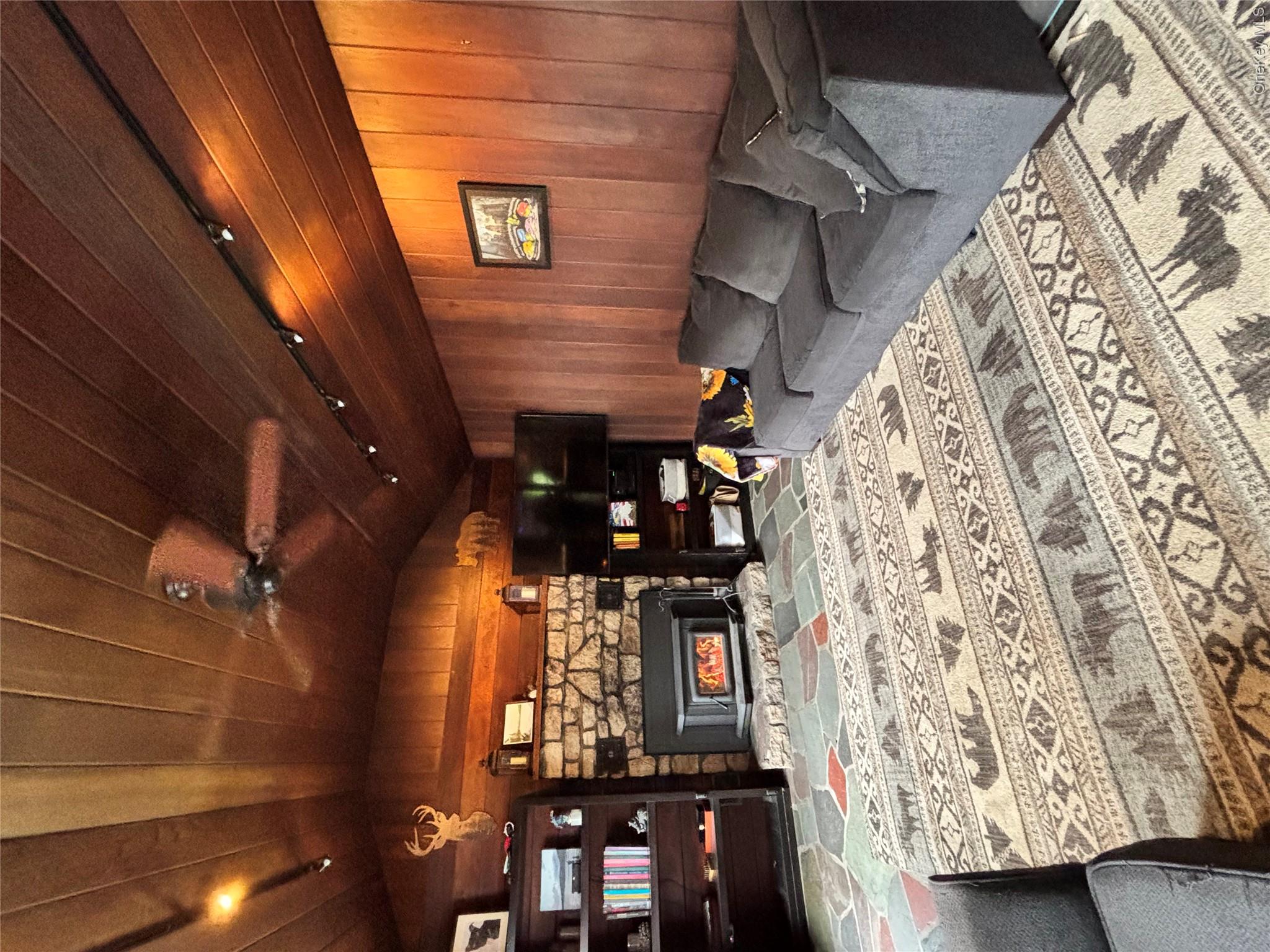 894 Upper Mountain Road Pine Bush, NY 12566 - Photo 10 of 35 Carpeted living room with vaulted ceiling, wood walls, a ceiling fan, rail lighting, and a stone fireplace