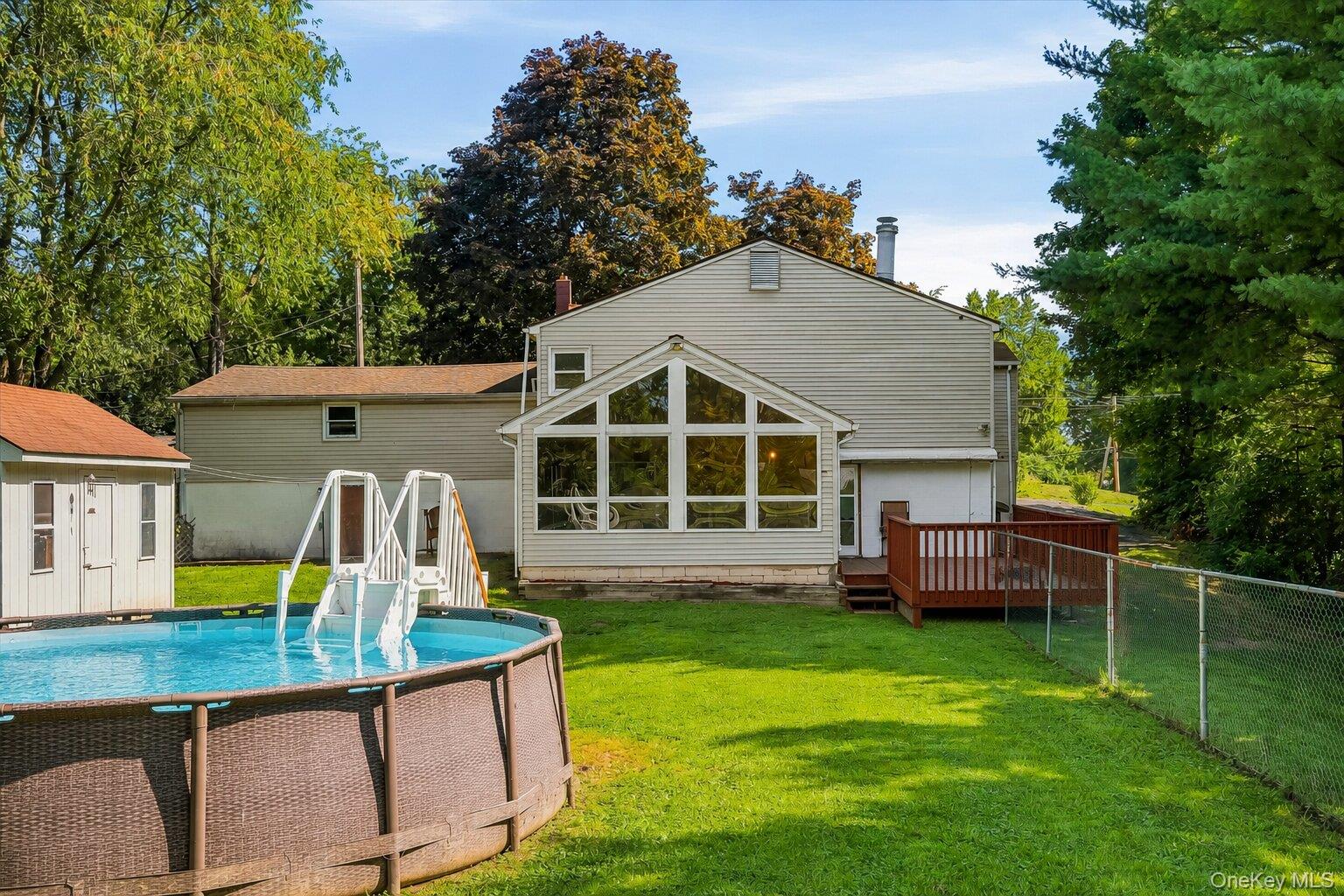 49 Chase Road Wallkill, NY 12589 - Photo 30 of 32 Spacious fenced backyard with an above-ground pool, storage shed, deck, and enclosed rear addition overlooking the property.