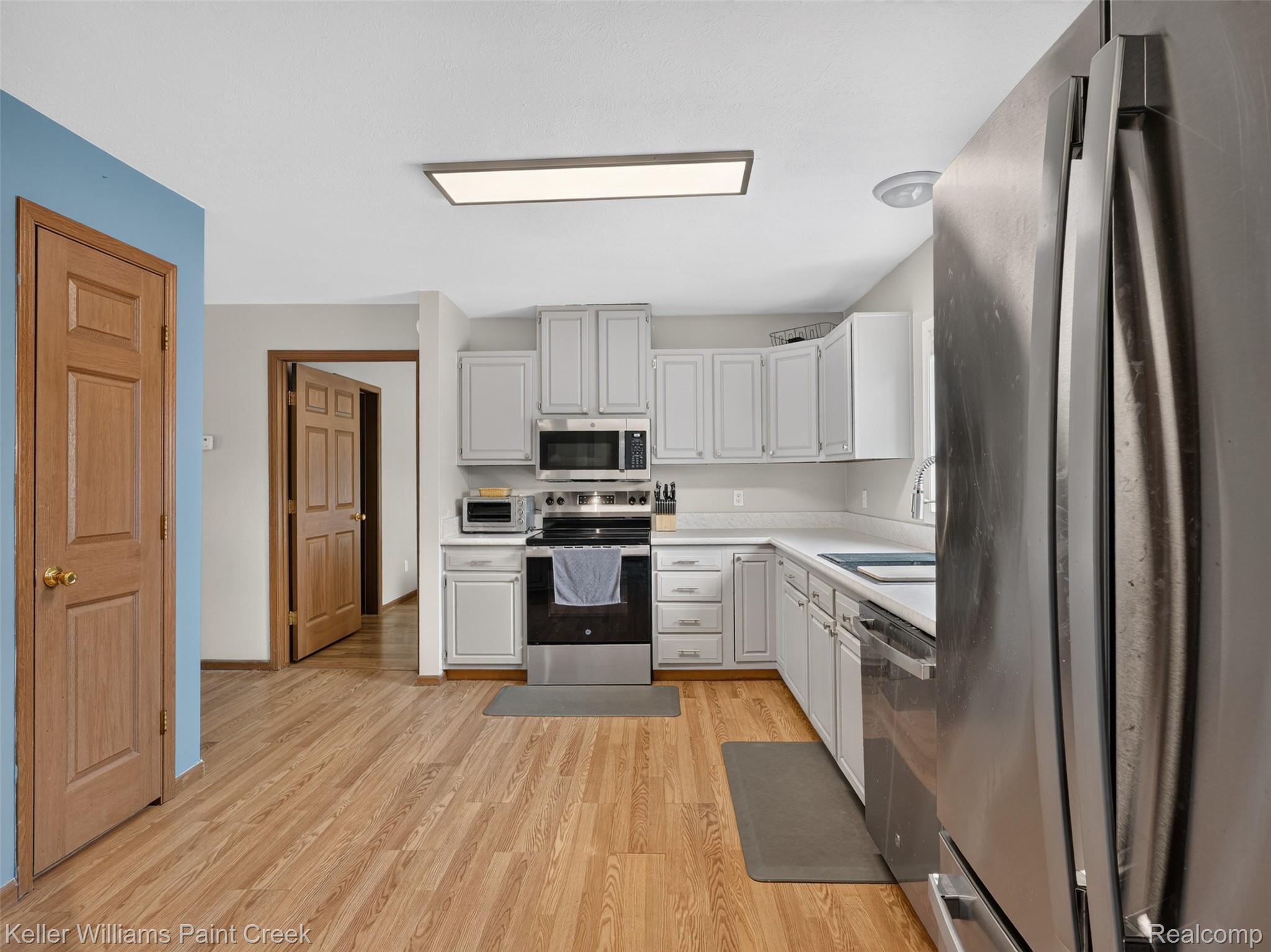 533 White Road Gladwin, MI 48624 - Photo 3 of 69 Open-concept kitchen island with white cabinetry and recessed lighting, anchored by a distinctive blue-gray accent wall with arched openings