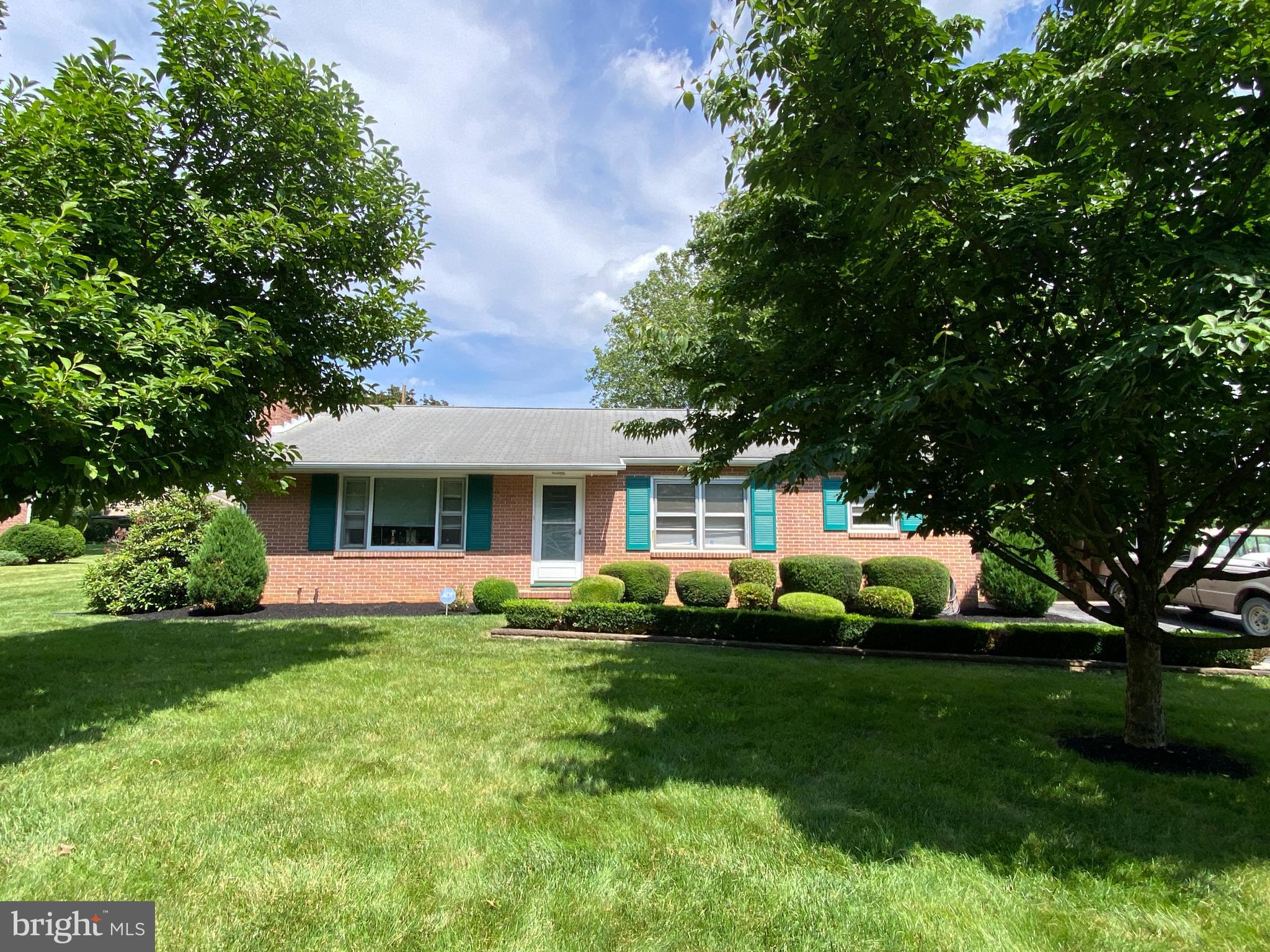 a front view of a house with a garden and trees