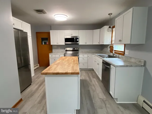 a kitchen with stainless steel appliances granite countertop a refrigerator a sink dishwasher a stove top oven a refrigerator and white cabinets