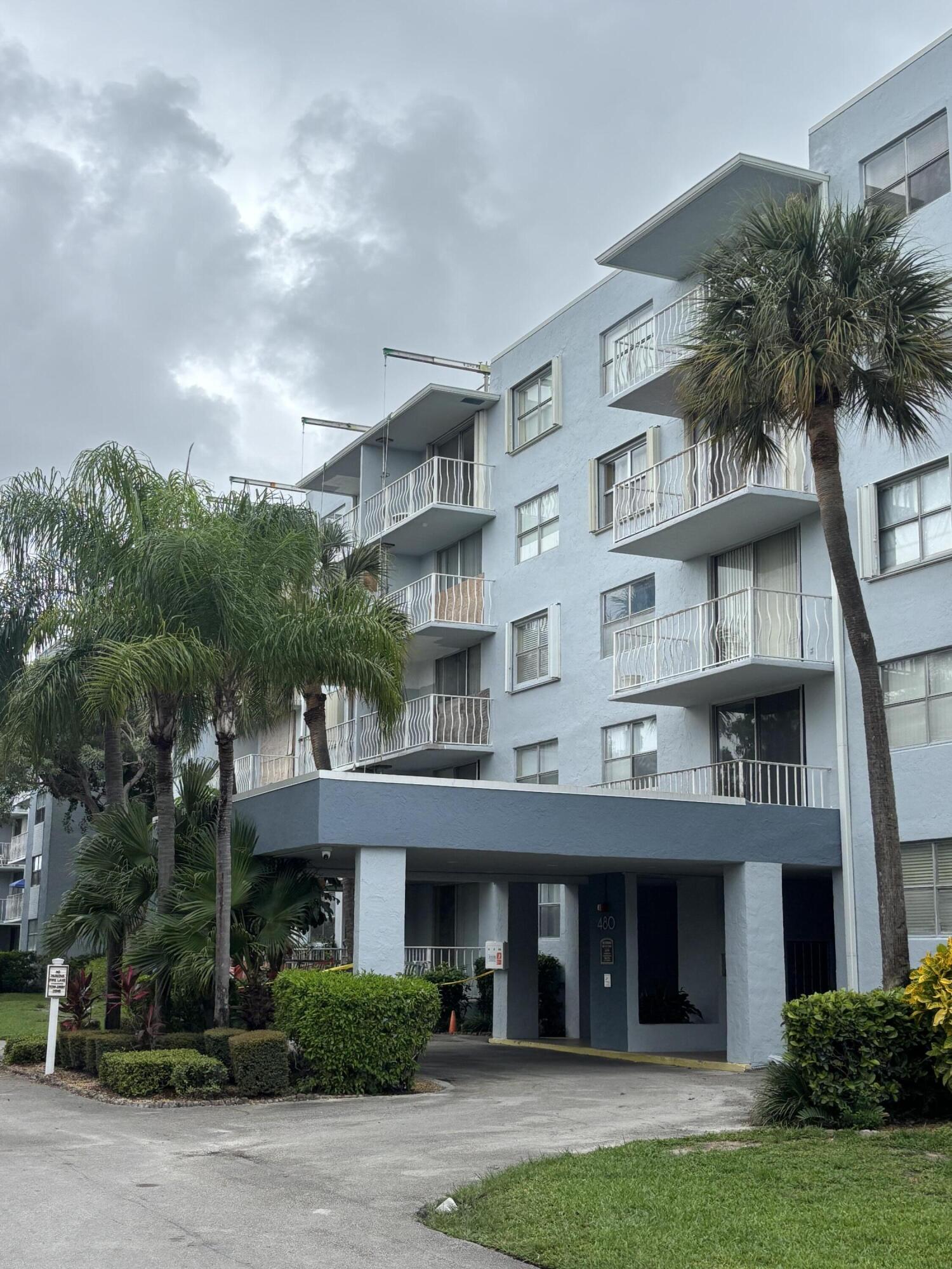 480 Executive Center Drive, Unit 2C West Palm Beach, FL 33401 - Photo 15 of 18 a front view of a residential apartment building with a yard