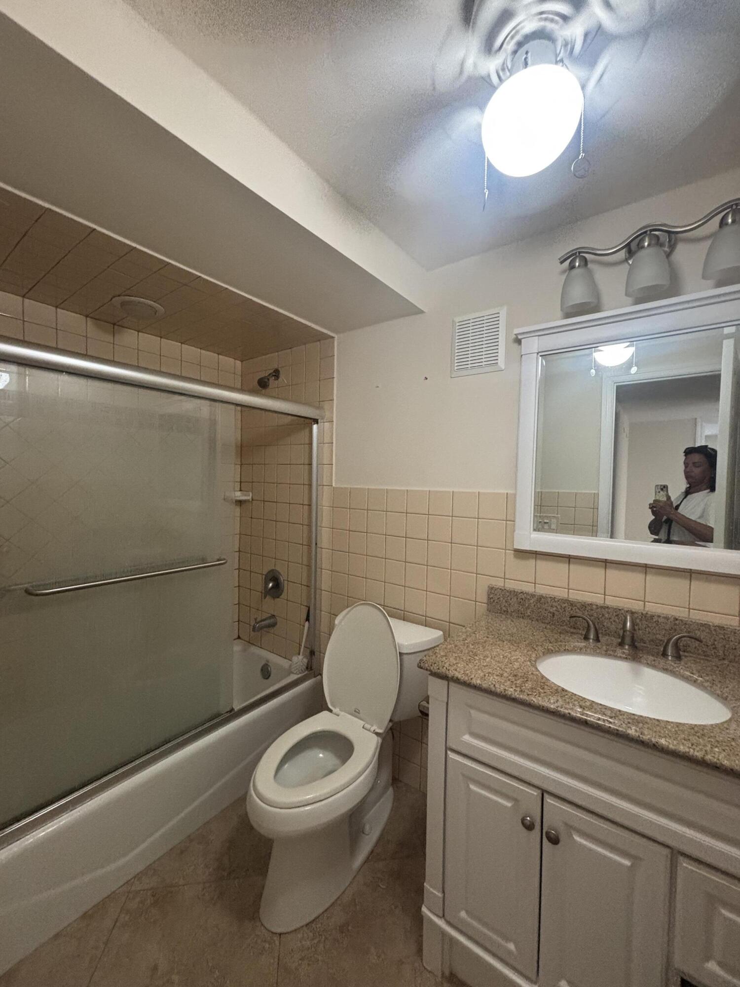 480 Executive Center Drive, Unit 2C West Palm Beach, FL 33401 - Photo 6 of 18 a bathroom with a granite countertop toilet sink and mirror