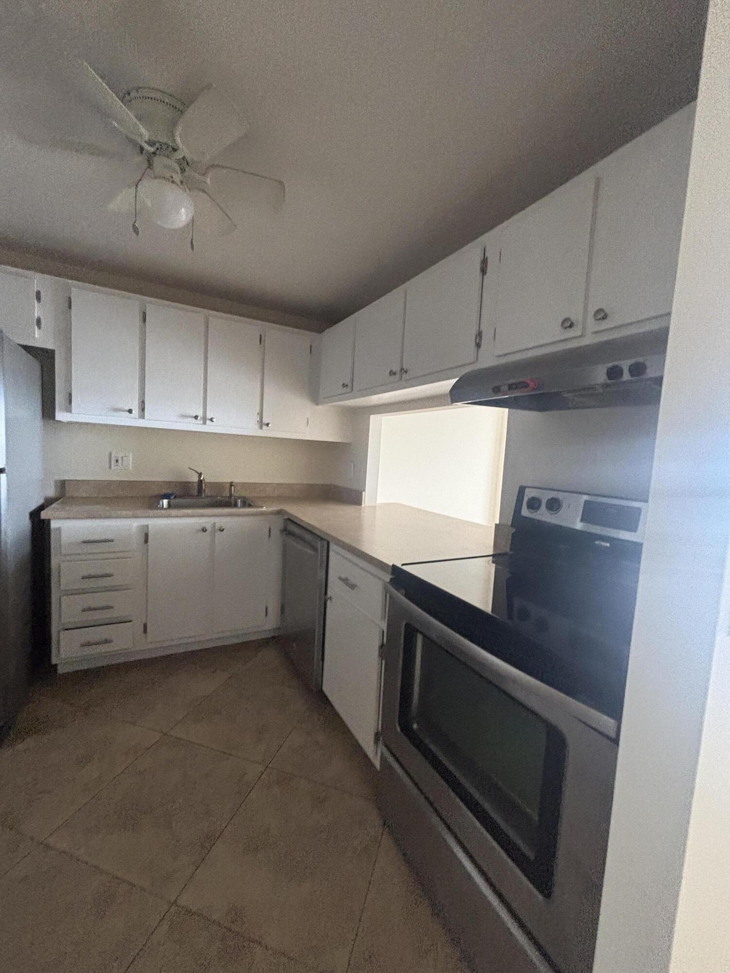 480 Executive Center Drive, Unit 2C West Palm Beach, FL 33401 - Photo 8 of 18 a kitchen with stainless steel appliances a stove a sink and white cabinets