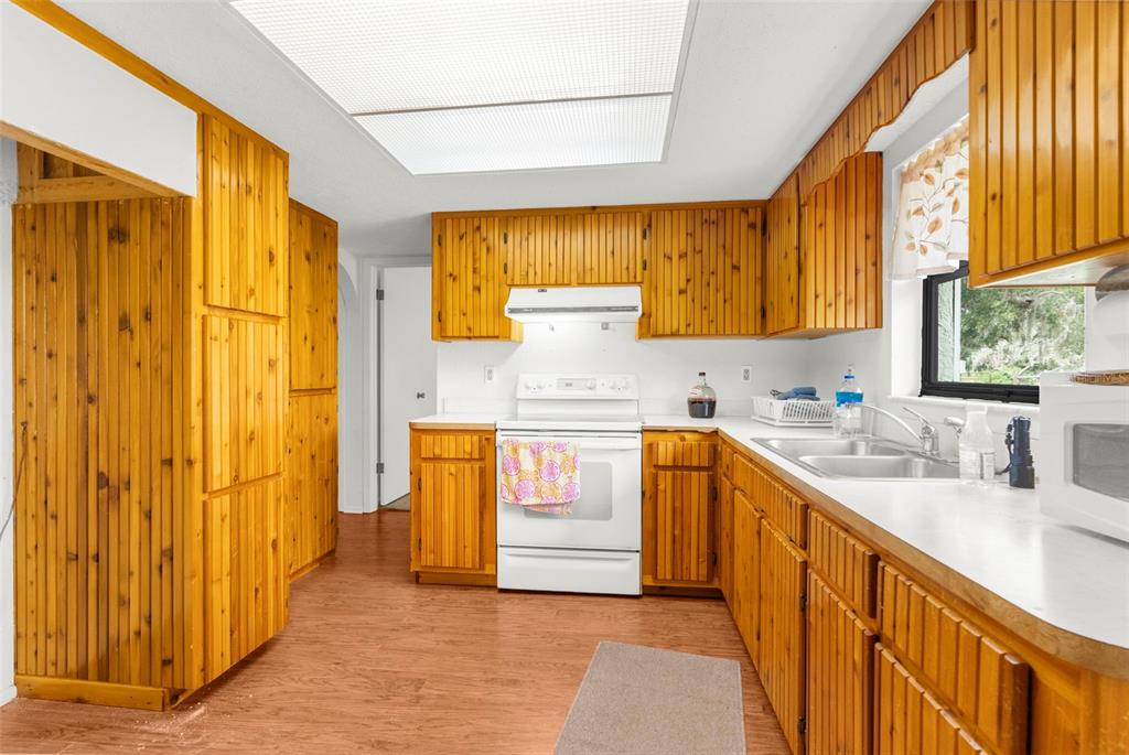 22249 Powell Road Brooksville, FL 34601 - Photo 14 of 43 a kitchen with a refrigerator a sink dishwasher and wooden cabinets