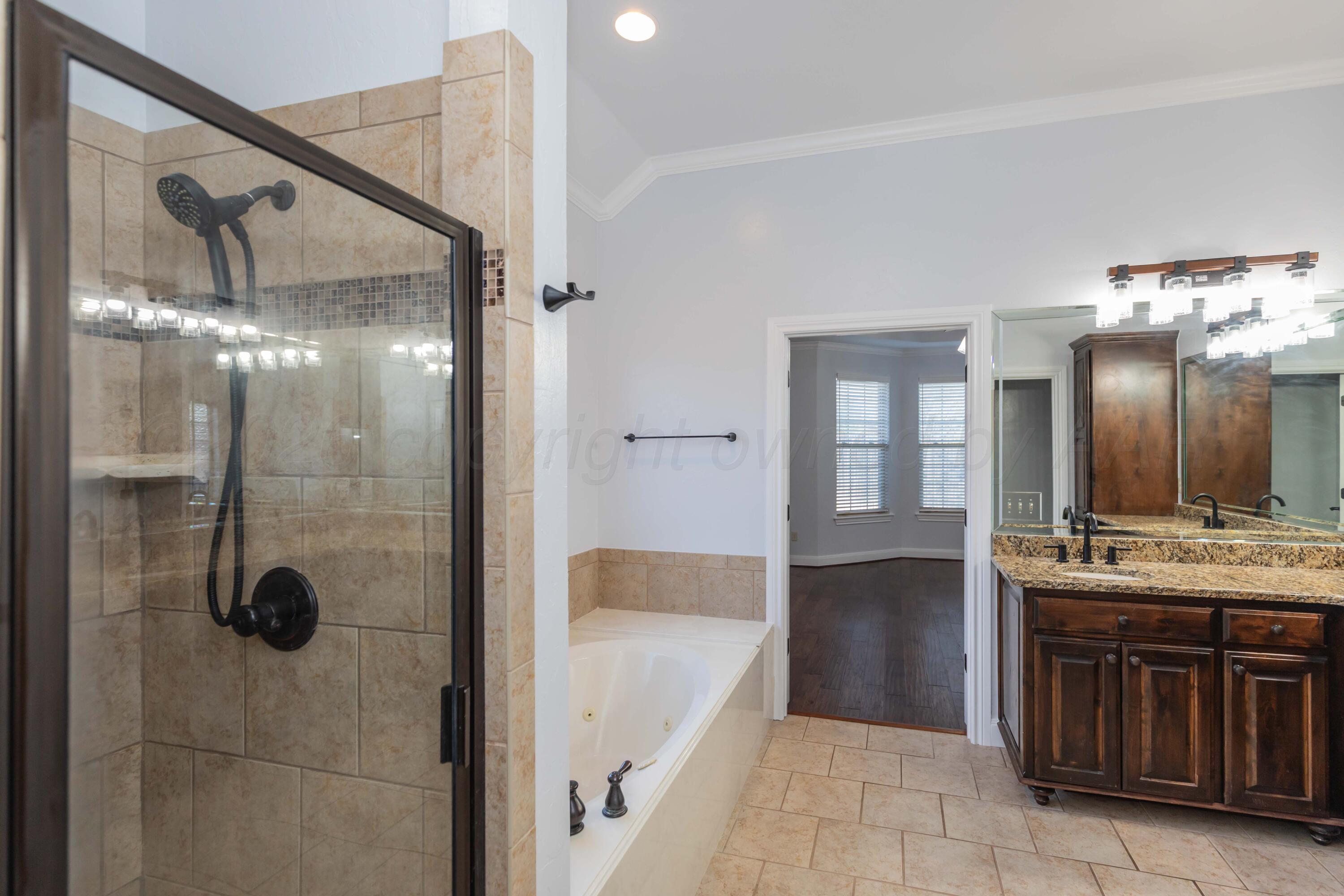 7718 Pinnacle Drive Amarillo, TX 79119 - Photo 33 of 66 a bathroom with a tub a sink and mirrors