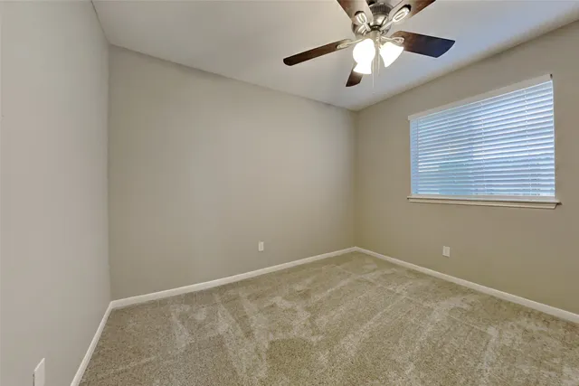 an empty room with a window and a fan
