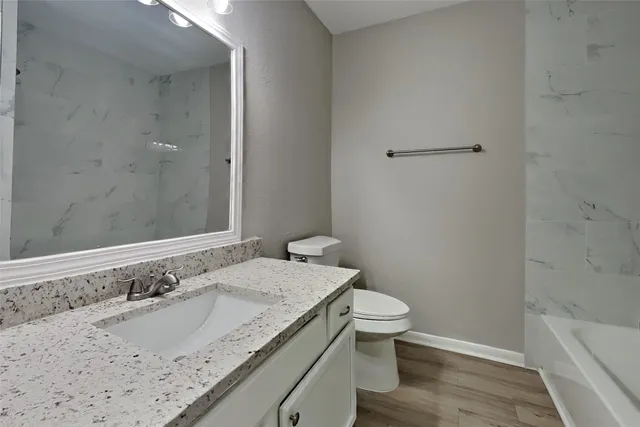 a bathroom with a granite countertop sink a toilet and shower