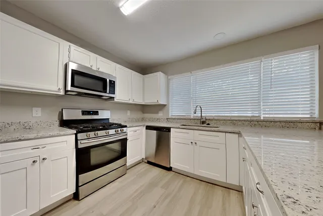 a kitchen with stainless steel appliances granite countertop a sink and stove top oven