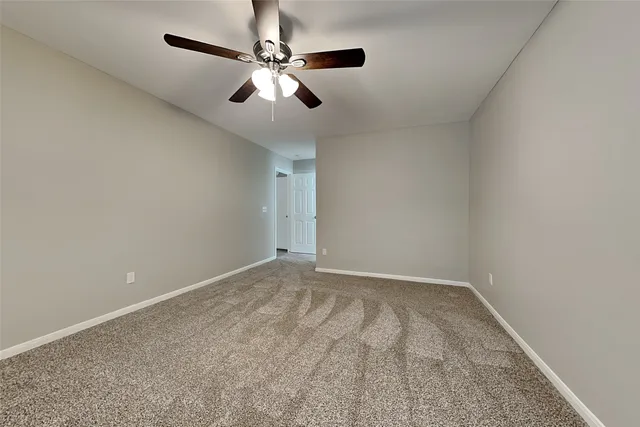 an empty room with a chandelier fan and windows