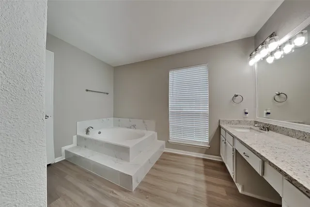a spacious bathroom with a granite countertop tub sink and mirror