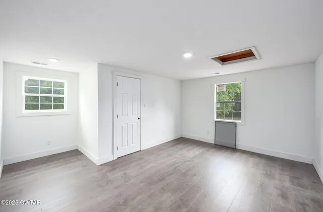 a large kitchen with stainless steel appliances kitchen island granite countertop a table chairs in it and wooden floors