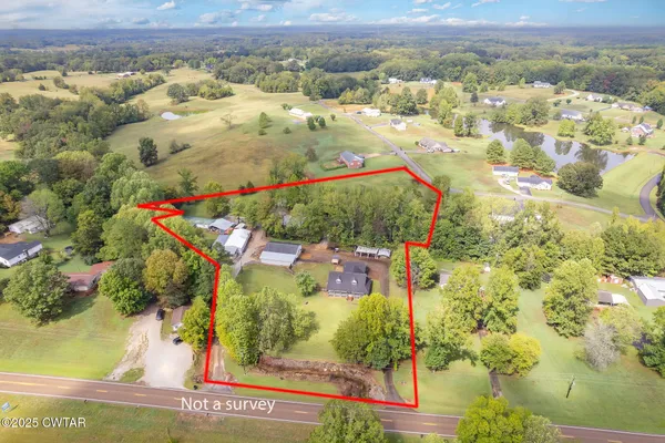 a view of a house with a wooden deck and a yard with a large tree