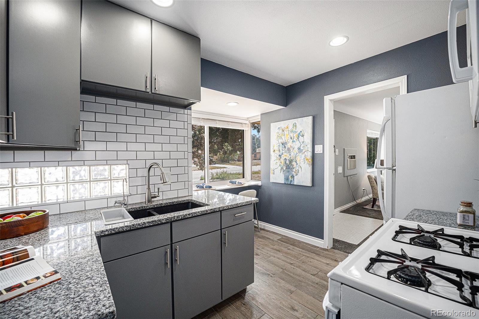 2141 Quebec Street Denver, CO 80207 - Photo 13 of 36 a kitchen with stainless steel appliances granite countertop a sink stove and refrigerator