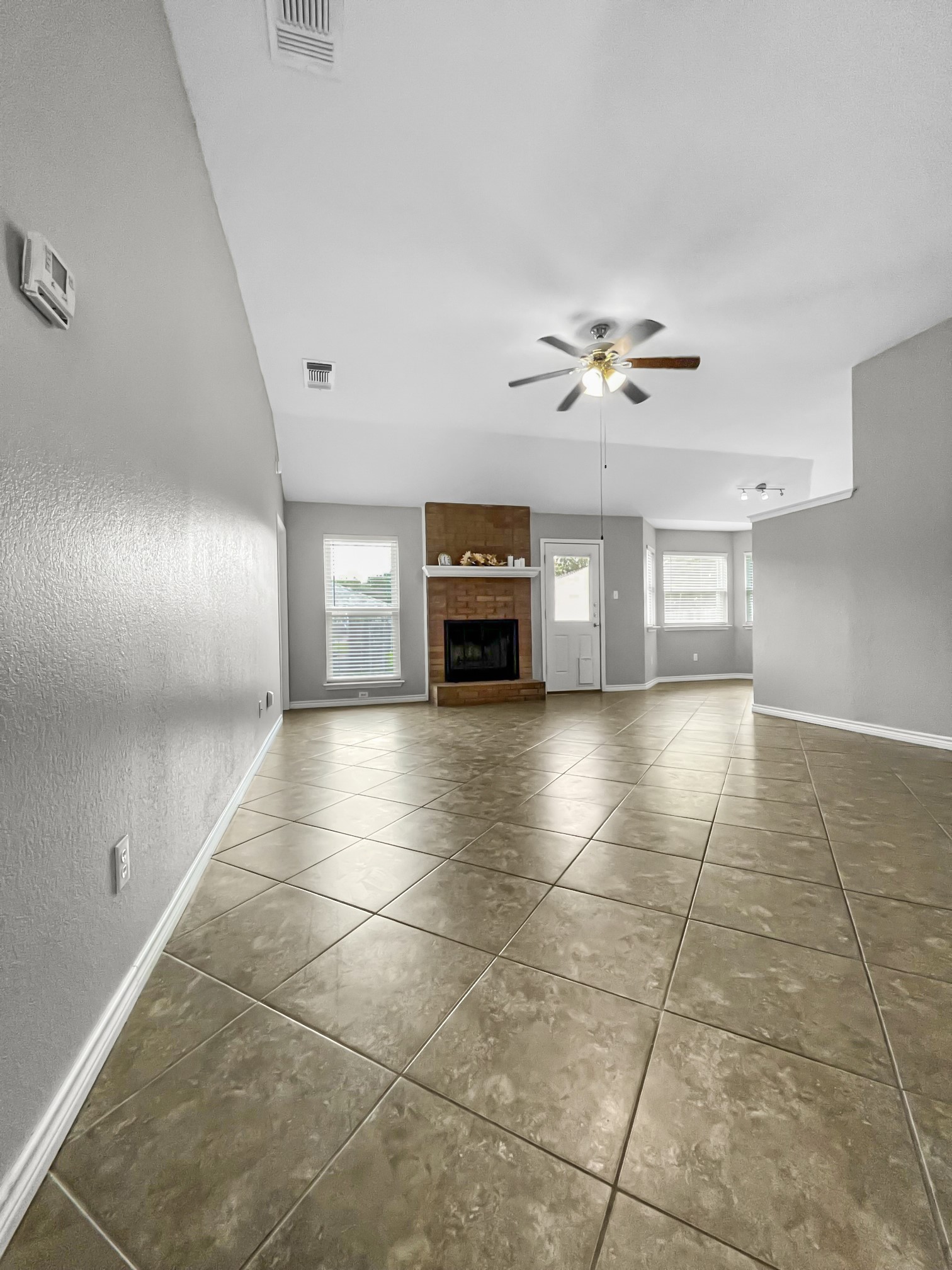 4701 High Pointe Drive Temple, TX 76502 - Photo 4 of 9 Unfurnished living room featuring a fireplace, a textured wall, tile patterned flooring, and a ceiling fan