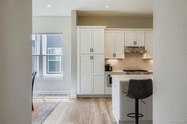 a kitchen with stainless steel appliances granite countertop a stove a refrigerator and white cabinets with wooden floor