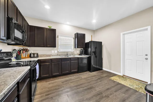 a kitchen with granite countertop a refrigerator stove top oven and sink