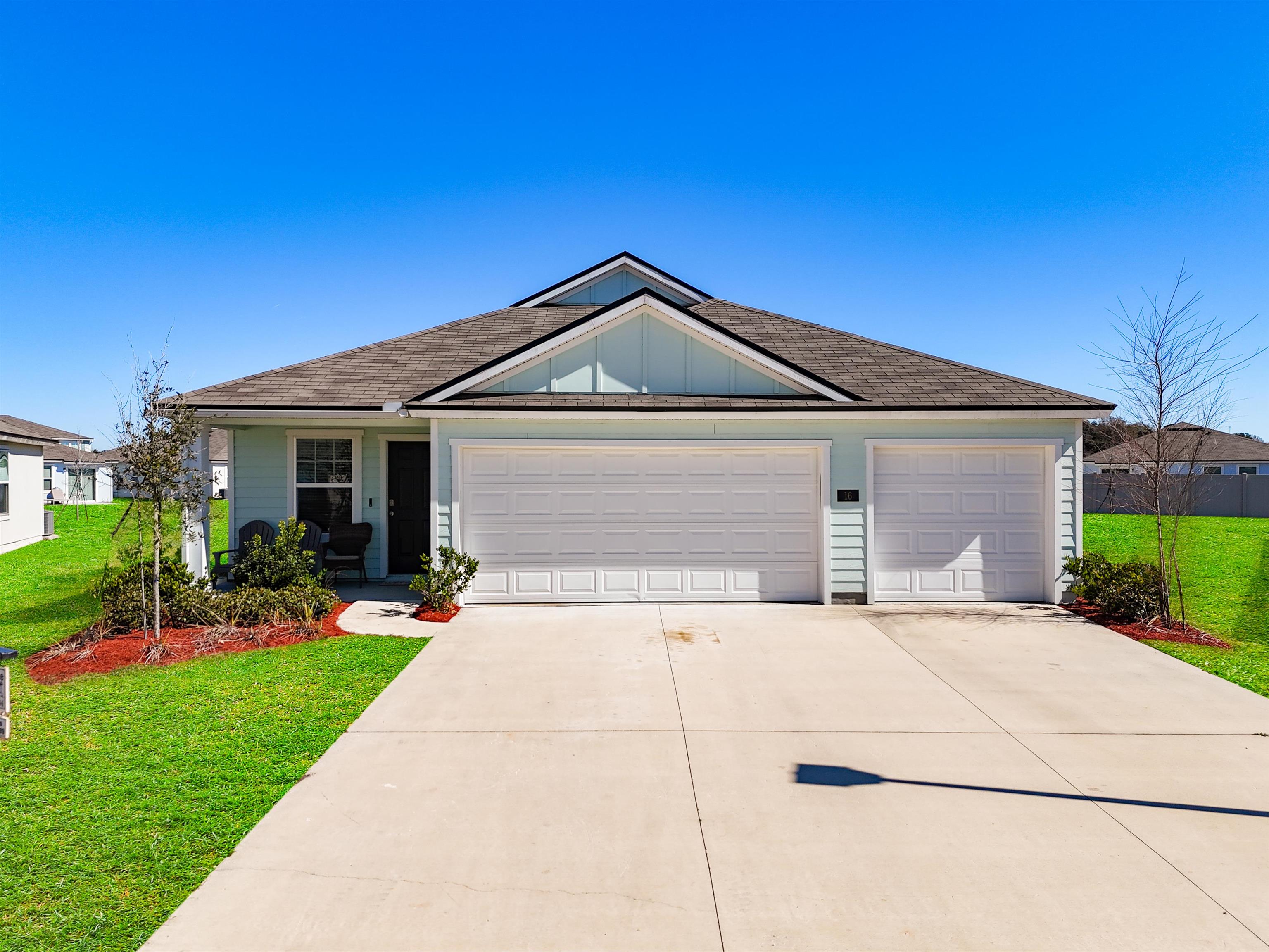 Ranch-style house featuring a front lawn, board and batten siding, roof with shingles, concrete driveway, and an attached garage